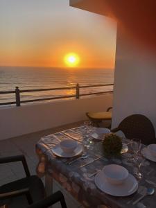 un tavolo con vista sull'oceano al tramonto di Cliff House next to beach a Ericeira