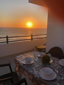 a table with a view of the ocean at sunset at Cliff House next to beach in Ericeira