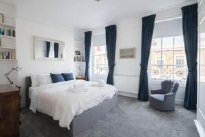 a bedroom with a large bed and a chair at Stylish Sloane Square Home Close to Victoria by UndertheDoormat in London