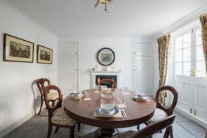 a dining room with a table and chairs and a fireplace at Stylish Sloane Square Home Close to Victoria by UndertheDoormat in London