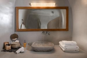 uma casa de banho com lavatório, espelho e toalhas em Adamant Suites em Fira