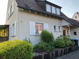 una casa con ventanas blancas con contraventanas y arbustos en BodenSEE Holiday Home Eriskirch, en Eriskirch