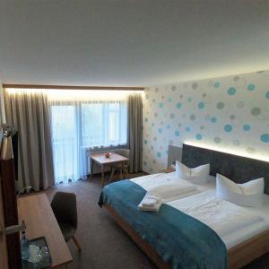 1 dormitorio con 1 cama grande, escritorio y mesa en Hotel Allgäu Garni, en Scheidegg