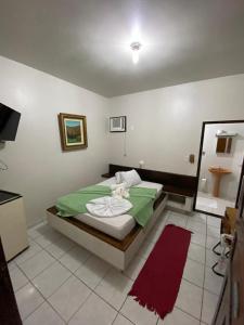 a bedroom with a green bed and a mirror at Hotel Rota Do Mar Inn Itajaí Navegantes in Itajaí