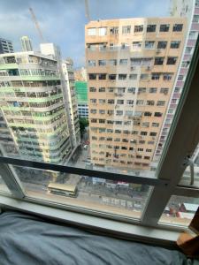 a window with a view of a city with tall buildings at Oasis Apartments in Hong Kong