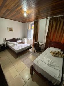 a bedroom with two beds and a table and a chair at Hotel Rota Do Mar Inn Itajaí Navegantes in Itajaí