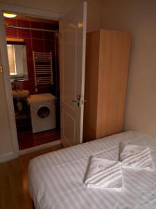 a bedroom with a bed and a bathroom with a washing machine at Mayfair Flat in London