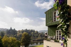 a woman standing on the balcony of a green house at Casa do Fontanário Stay in Amarante