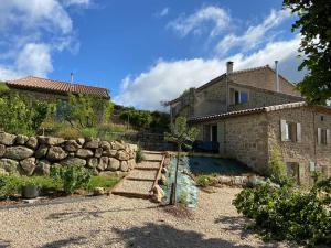a stone house with a stone wall next to a house at Gites de l'alouette in Boffres