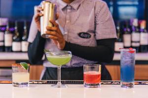 ein Barkeeper, der ein Foto von Cocktails auf einer Bar macht in der Unterkunft Holiday Inn Philadelphia-Cherry Hill, an IHG Hotel in Cherry Hill