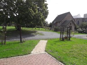 a brick walkway in front of a house with a building at La ferme de la Baconnerie in Sainte-Marguerite-dʼElle