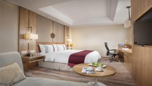a hotel room with a bed and a table at Holiday Inn Hefei by IHG in Hefei