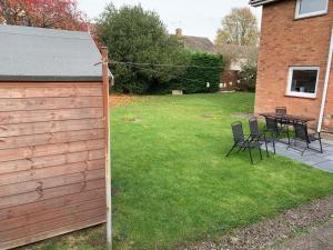 a backyard with a fence and a table and chairs at 5 bedrooms, 2 Reception Rooms, 2 Shower Rooms, Sleeps up to 7, Parking, Free WiFi & Netflix, Large Garden in Corby