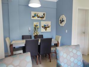 邦比尼亞斯的住宿－Bombinhas Centro, apartamento 02 dorm, ótima localização，一间拥有蓝色墙壁和桌椅的用餐室