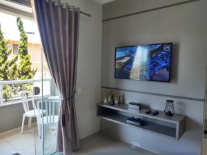 a living room with a tv on a wall at Bombinhas Centro, apartamento 02 dorm, ótima localização in Bombinhas