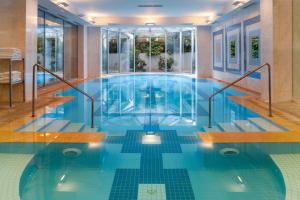 a swimming pool with a blue tile floor and windows at Holiday Inn Athens Attica Av, Airport W., an IHG Hotel in Athens