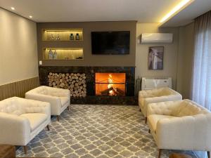a living room with a fireplace and chairs and a tv at Pousada Brombatti in Nova Petrópolis
