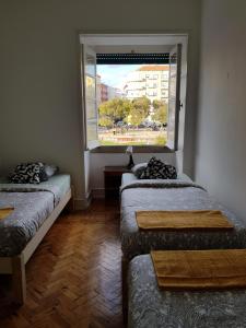 two beds in a room with a window at Rose view guest house in Lisbon