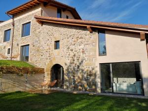 a stone house with glass doors and a yard at Oribar Casa Rural in Aia