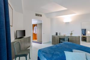 Schlafzimmer mit einem Bett und einem Schreibtisch mit einem TV in der Unterkunft Rada Siri in Montepaone