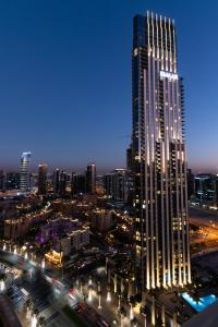 a lit up skyscraper in a city at night at Quintessential Quarters: 29th Fl Views - Walk to Opera, Mall and Burj Khalifa in Dubai
