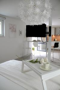 a white living room with a table and a tv at Appartement Blanc cocooning in Sprimont