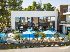 a building with blue umbrellas in front of a pool at Olive Tree mansion in Vir