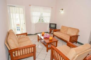 a living room with chairs and a couch and a tv at Caribbean Inn and Suites in Saint Johnʼs