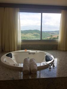 a bath tub with two towels on a table with a window at Hotel Mirante São Brás in São Brás do Suaçuí