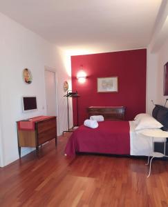 sypialnia z czerwoną ścianą z łóżkiem i biurkiem w obiekcie Penta Luxury Room w mieście Matera