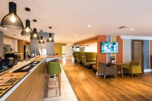 a lobby with a bar and green chairs at Holiday Inn Chester South by IHG in Chester
