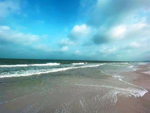 una playa de arena con olas en el océano en Nautical Watch, en Clearwater Beach