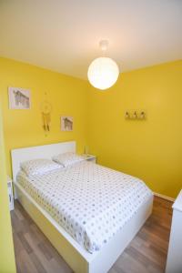 1 dormitorio con paredes amarillas y 1 cama blanca en Appartement "le Terminus " Gare-Cosy-Wifi 6 Personnes en Saint-Quentin