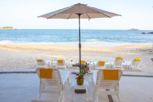 a table with chairs and an umbrella on the beach at Hotel Castillo Huatulco & Beach Club in Santa Cruz Huatulco