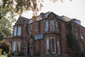 an old brick house with a sign in front of it at Pinegrove Hotel in Carlisle