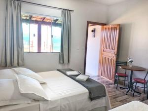 1 dormitorio con cama, mesa y ventana en Brisa do Lago Pousada en Capitólio