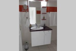 een witte badkamer met een wastafel en een spiegel bij Gîtes de Corneille, Bungalow Sweet Mango in Le Moule