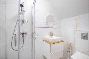 a white bathroom with a shower and a sink at Rezydencja nad rzeką in Łeba