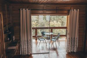 a table and chairs in a room with a large window at Chalés Requinte em Pedra Azul in Pedra Azul