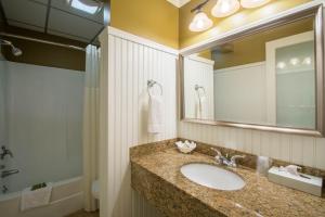 a bathroom with a sink, mirror and bath tub at Anchorage Inn and Suites in Portsmouth