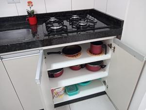 una cucina con piano cottura e alcune pentole e padelle di Meu Apê Maringá - UEM - Perto de tudo! a Maringá
