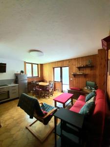 a living room with a red couch and a kitchen at Sweet Home ski out in Valtournenche