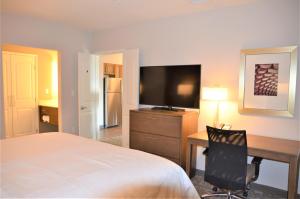 een slaapkamer met een bed, een bureau en een televisie bij Staybridge Suites - Orenco Station, an IHG Hotel in Hillsboro