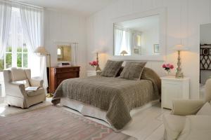 a bedroom with a bed and a chair and a mirror at La Baronnie Hôtel & Spa - Teritoria in Saint-Martin-de-Ré