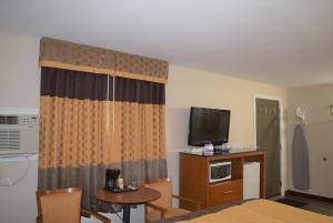 a hotel room with a television and a table and chairs at Knights Inn Arnprior in Arnprior