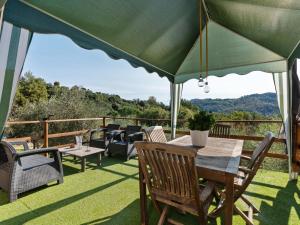 un patio con mesa y sillas bajo una sombrilla verde en Belvilla by OYO Casa Polvere di Stelle, en Monsagrati