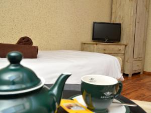 um bule de chá e uma chávena numa mesa num quarto em KAMIENICA Pokoje & Restauracja em Opalenica