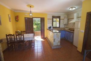 cocina con paredes amarillas, mesa y sillas en Casas el Albarracín, en El Bosque 24 fotos más