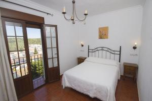a bedroom with a white bed and a balcony at Casas el Albarracín in El Bosque