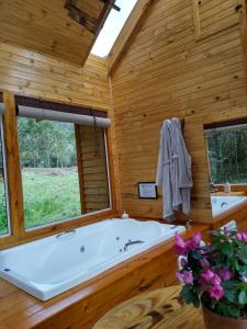 a large bath tub in a wooden room with a window at Chalés Estância Cachoeira do Avencal in Urubici